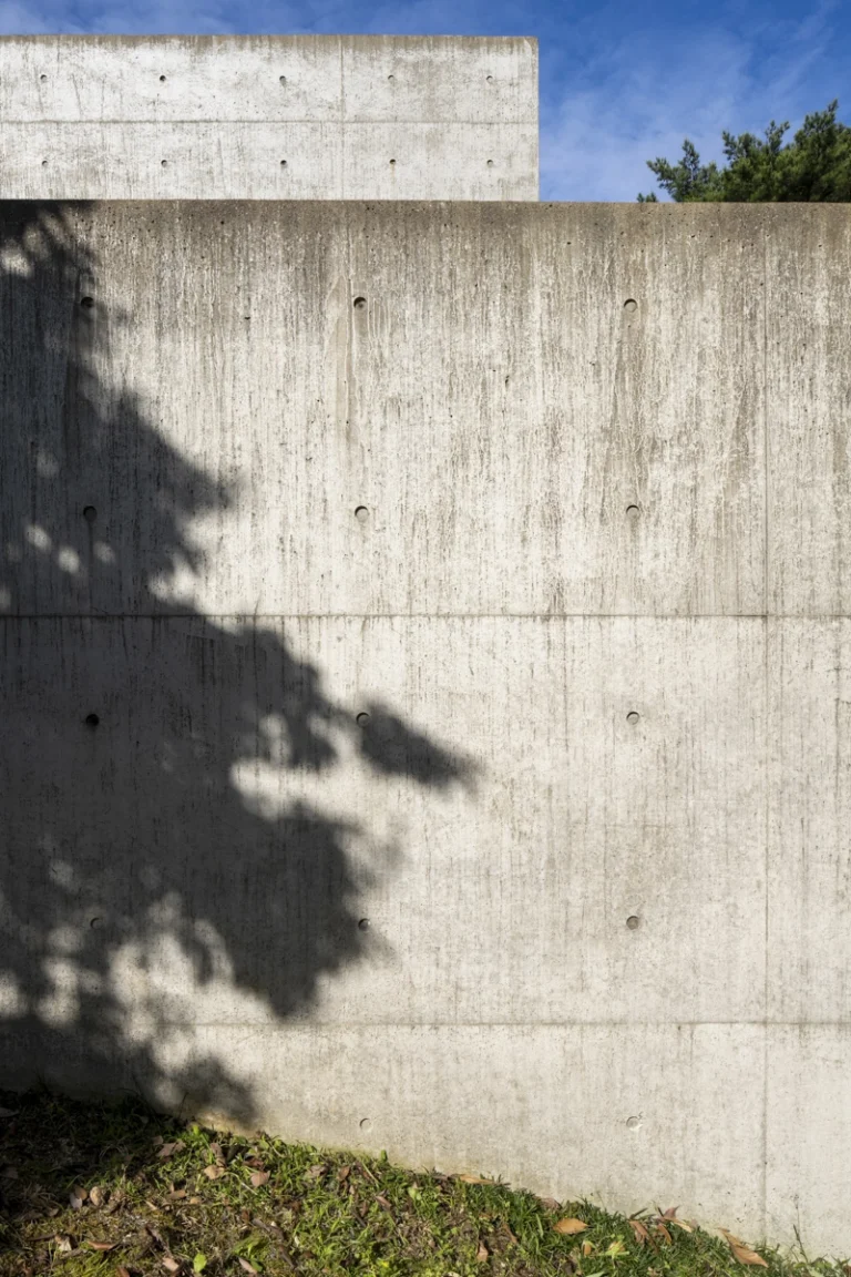 Deed Studio, an award-winning architecture photography studio based in Dubai and the GCC, captures the Koshino House by Tadao Ando—a minimalist concrete home set into a wooded hillside, defined by curved and rectilinear forms and soft natural light filtering through narrow skylights